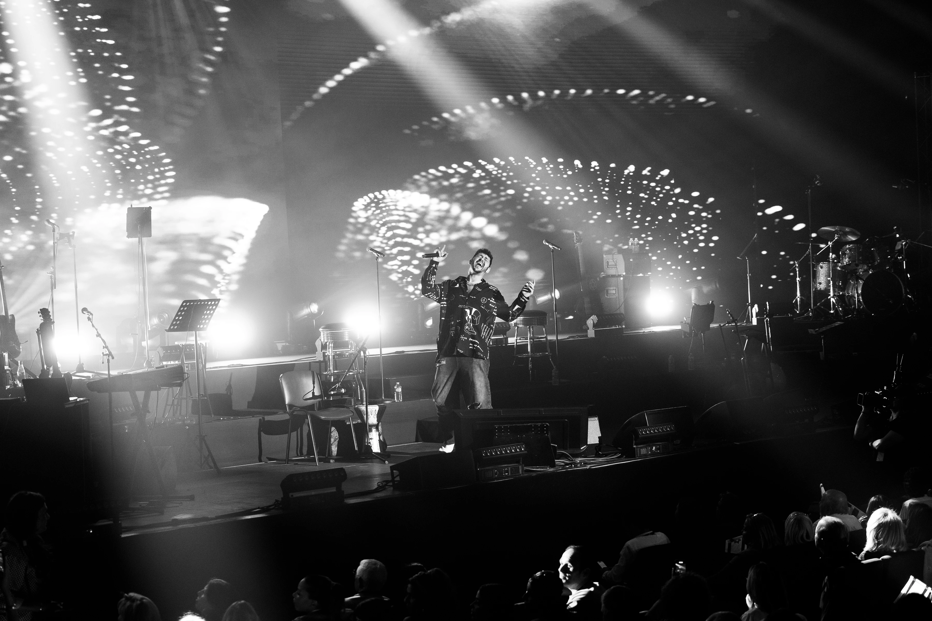 Chanteur sur scène sous les lumières, en noir et blanc
